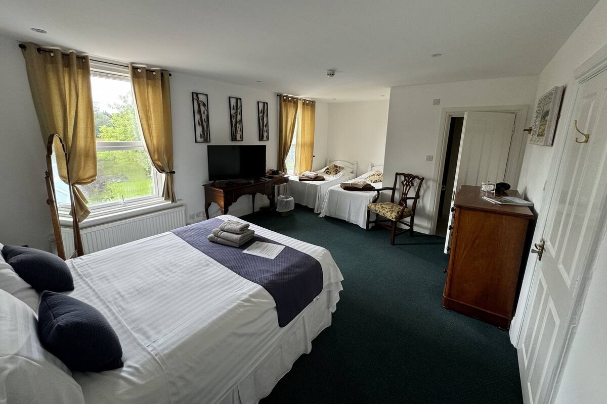 A hotel room with two beds, a desk, a chair, and a television.