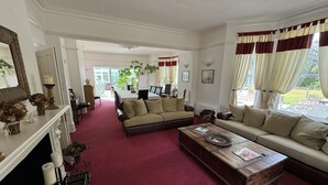 A spacious living room with a red carpet, two sofas, a coffee table, and a fireplace. - Hookwood Lodge (Horley)