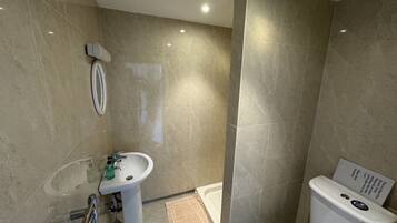 Une salle de bain comprenant un lavabo, des toilettes et un espace douche.