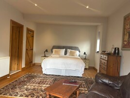 A bedroom with a bed, bedside tables, a dresser, a patterned rug, and a leather sofa.