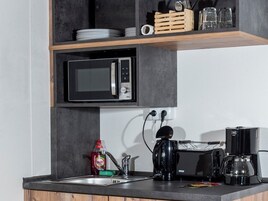 Cozinha equipada com micro-ondas, máquina de café e torradeira.