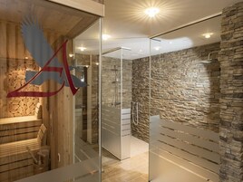 A modern spa with a stone wall, a wooden sauna area, and a glass partition.