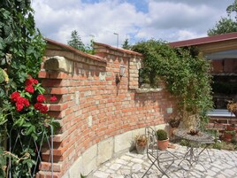 A brick wall with climbing plants, a metal table, and potted plants.