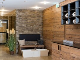 Uma casa de banho moderna com parede de pedra, armários de madeira, banheira e pia.