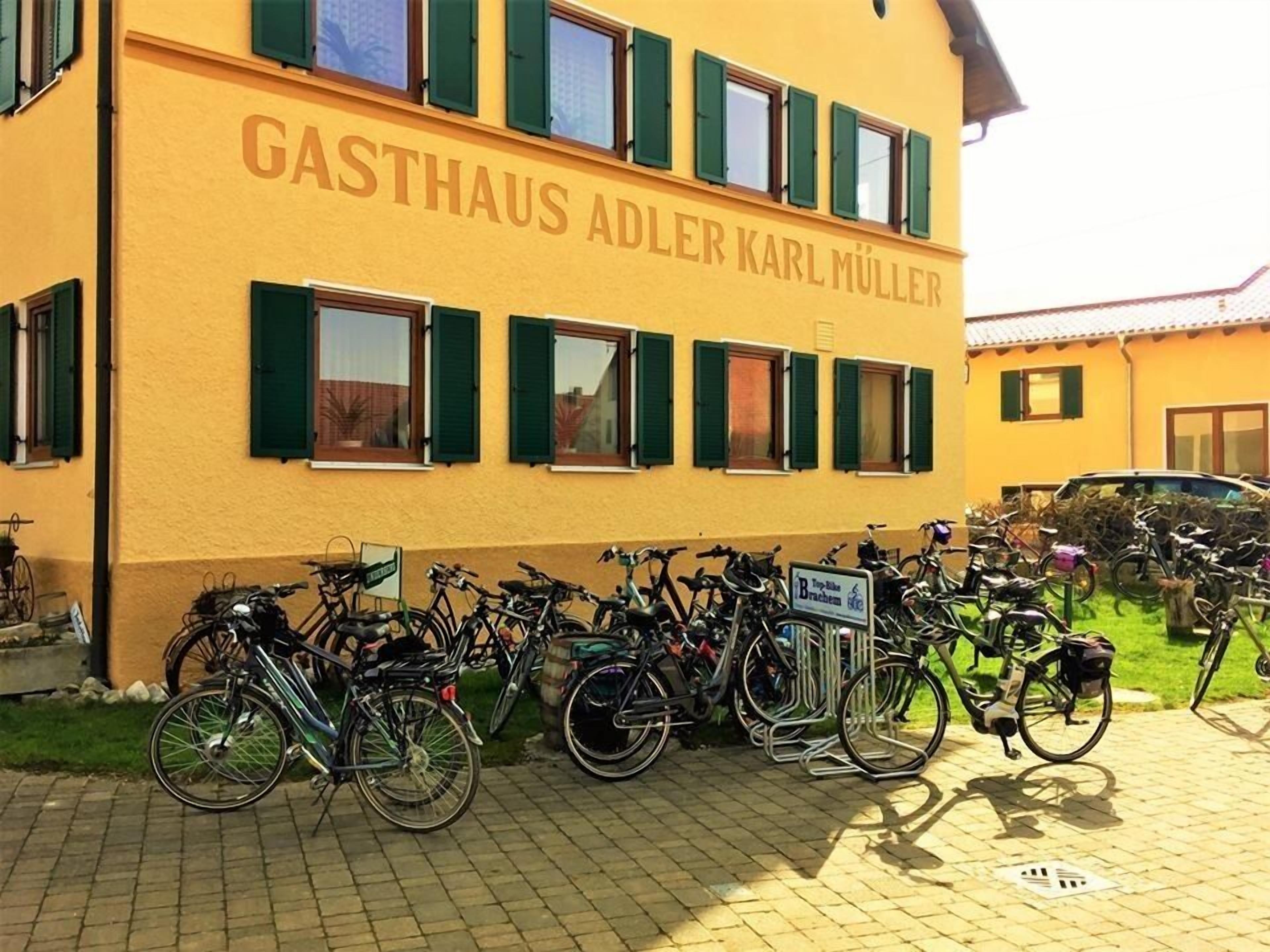 A building named GASTHAUS ADLER KARL MÜLLER with multiple bicycles parked outside.