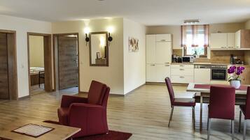Un apartament modern amb zona de menjador, cuina i saló amb cadires vermelles i una taula de fusta.