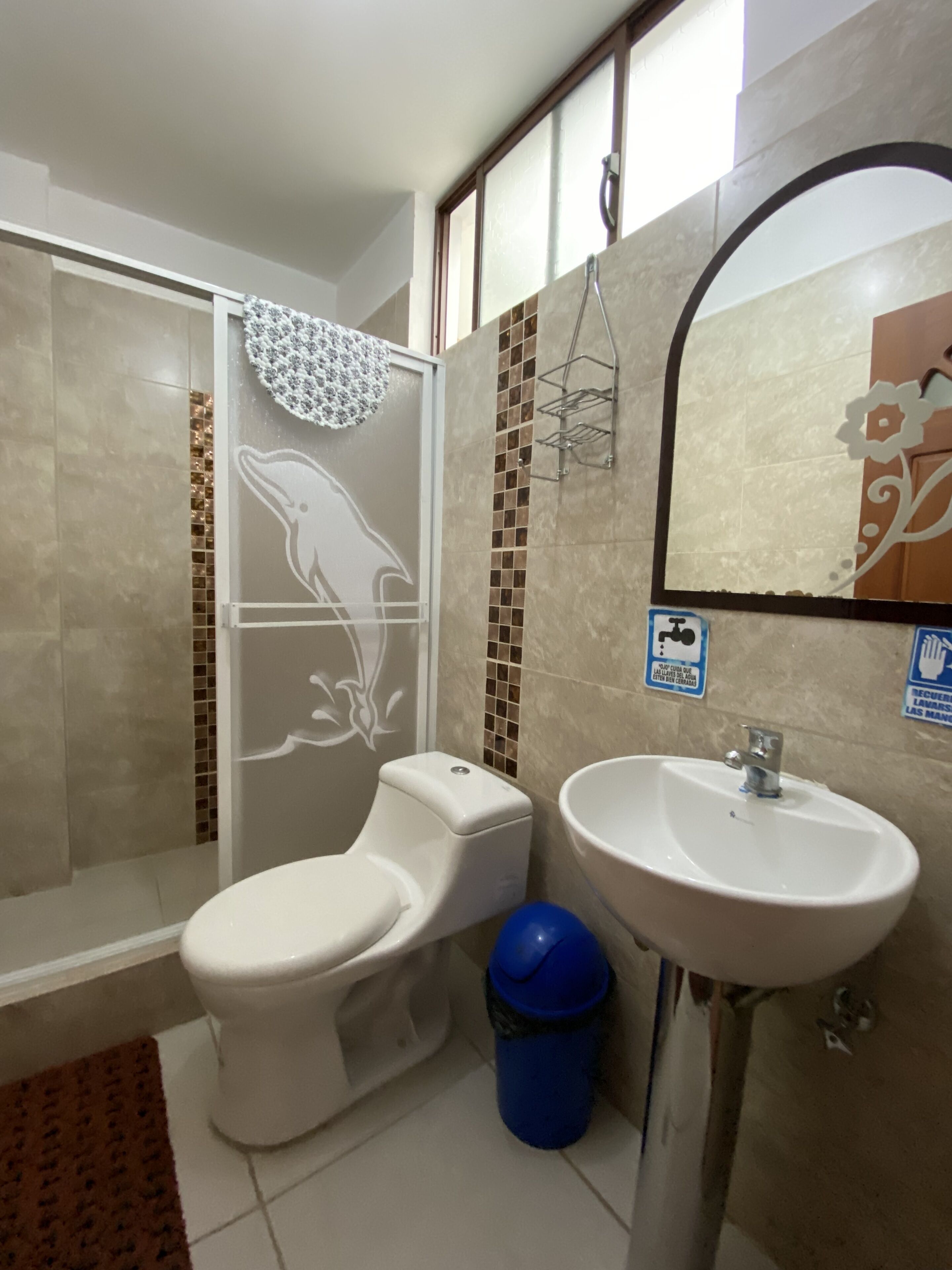 A bathroom with a toilet, shower, and sink.