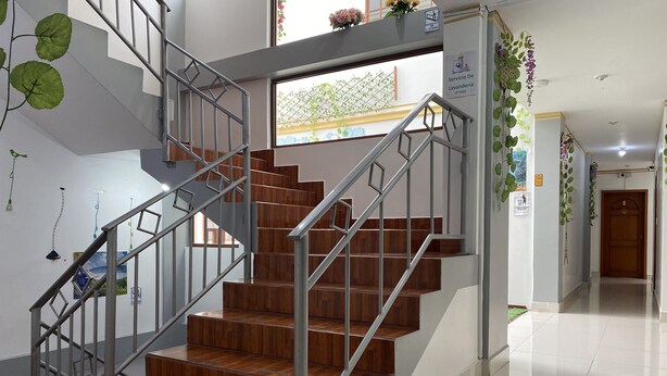 Una escalera moderna con escalones de madera y barandillas de metal, que sube a un piso superior.