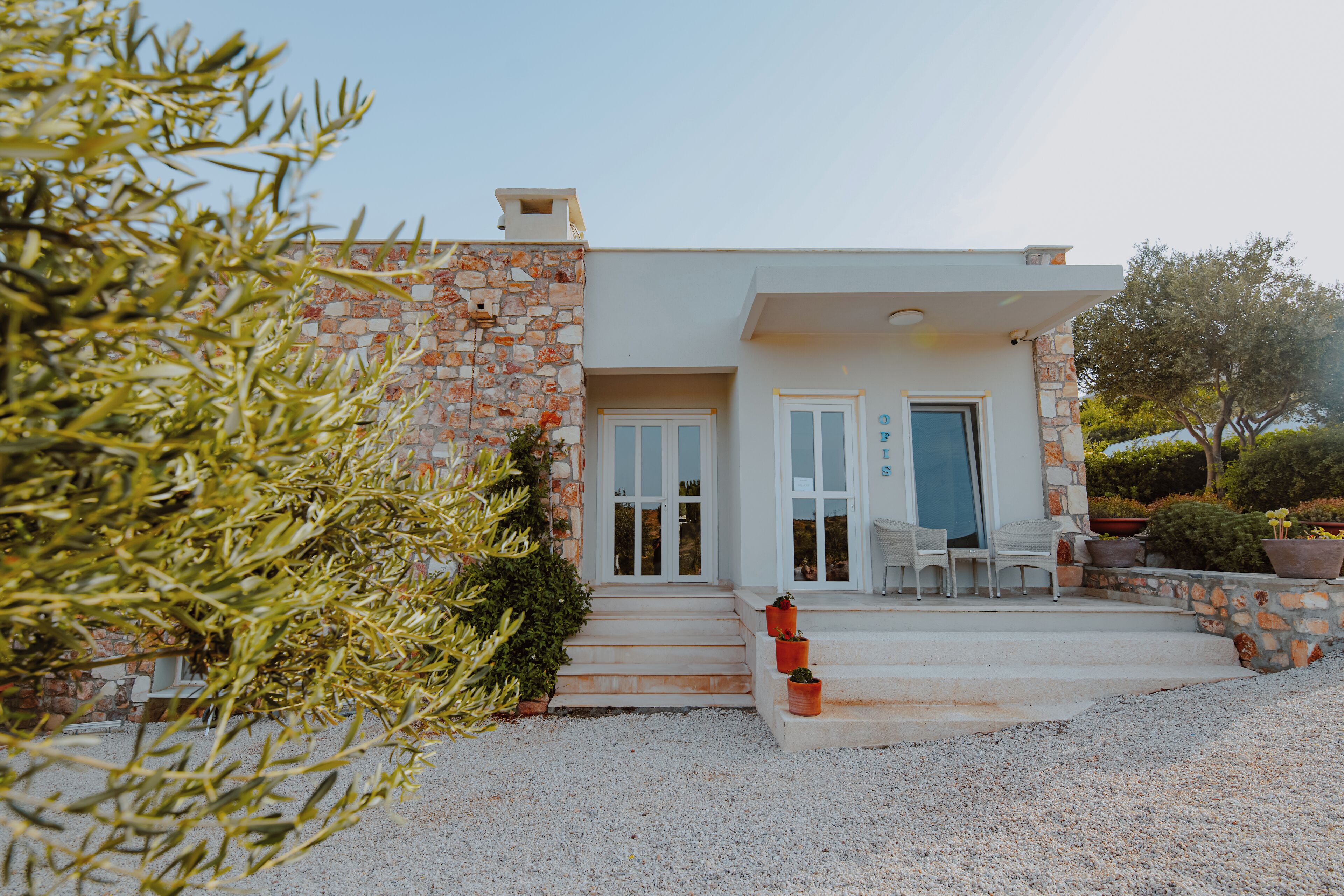A modern house with a stone facade, a front porch with steps, and outdoor seating.