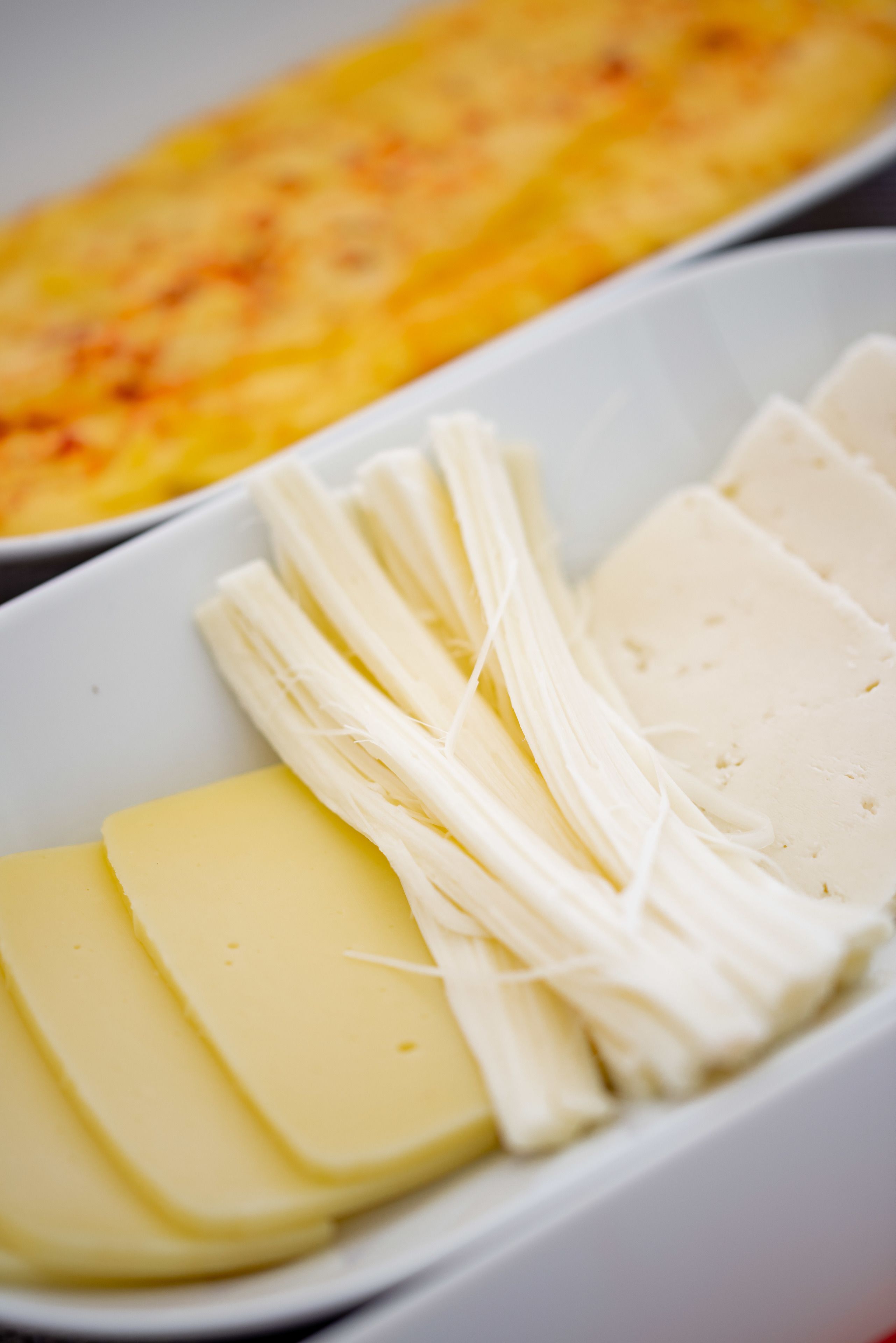 Un plato blanco con rebanadas de queso y un hilo de queso.