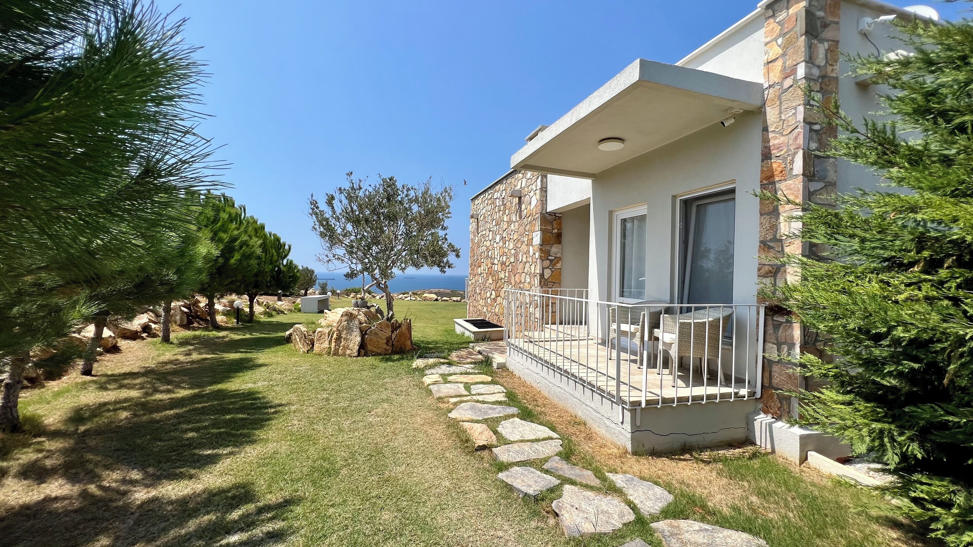 A stone building with a balcony, a stone pathway, and a view of the sea.
