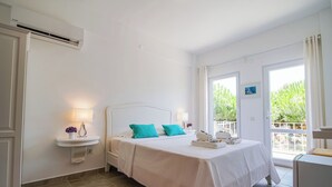 A bedroom with a bed, bedside table, lamp, and an air conditioning unit. - Aika Akvaryum (Bozcaada)
