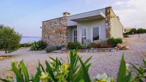 Una casa moderna con fachada de piedra, un porche delantero y vista al mar.