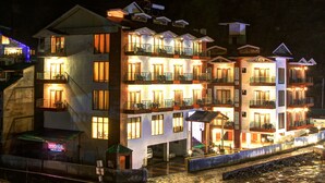 A multi-story hotel with balconies, a swimming pool, and a waterfront view. - Hill County Resort & Spa, Manali (Manali)