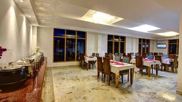 A dining area with marble flooring, wooden chairs, and tables set for a meal.