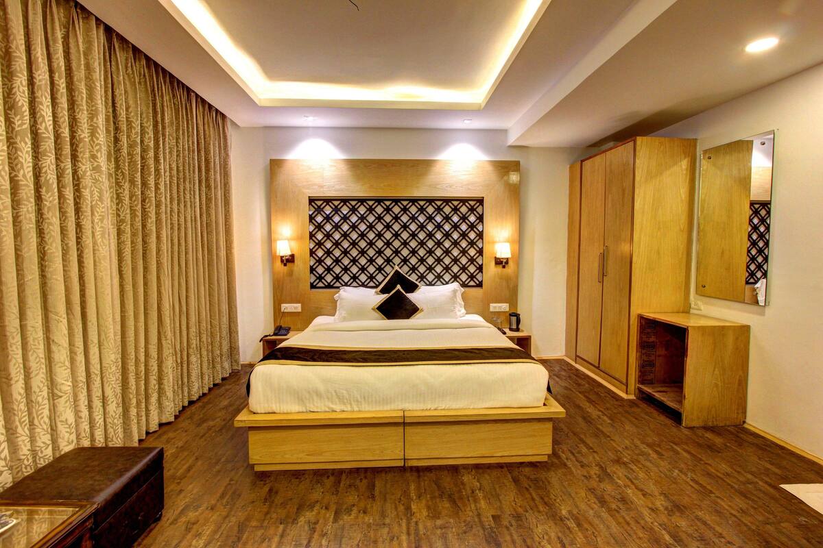 A modern bedroom with a large bed, wooden wardrobe, and a mirror.