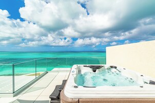 Un jacuzzi en un balcón con vista despejada al océano y al cielo.