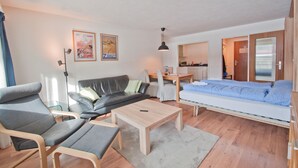Una sala moderna con un sofá, sillas, una mesa de centro y una cama.