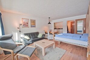 Ett modernt vardagsrum med en soffa, fåtöljer, ett soffbord och en säng.