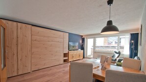 Una cocina moderna con armarios de madera, una zona de comedor con sillas a cuadros y un ventanal con vistas.