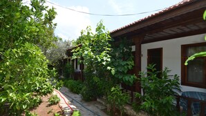 A garden with various plants and a small table with a blue checkered tablecloth. - Umut Otel & Beach (Marmaris)