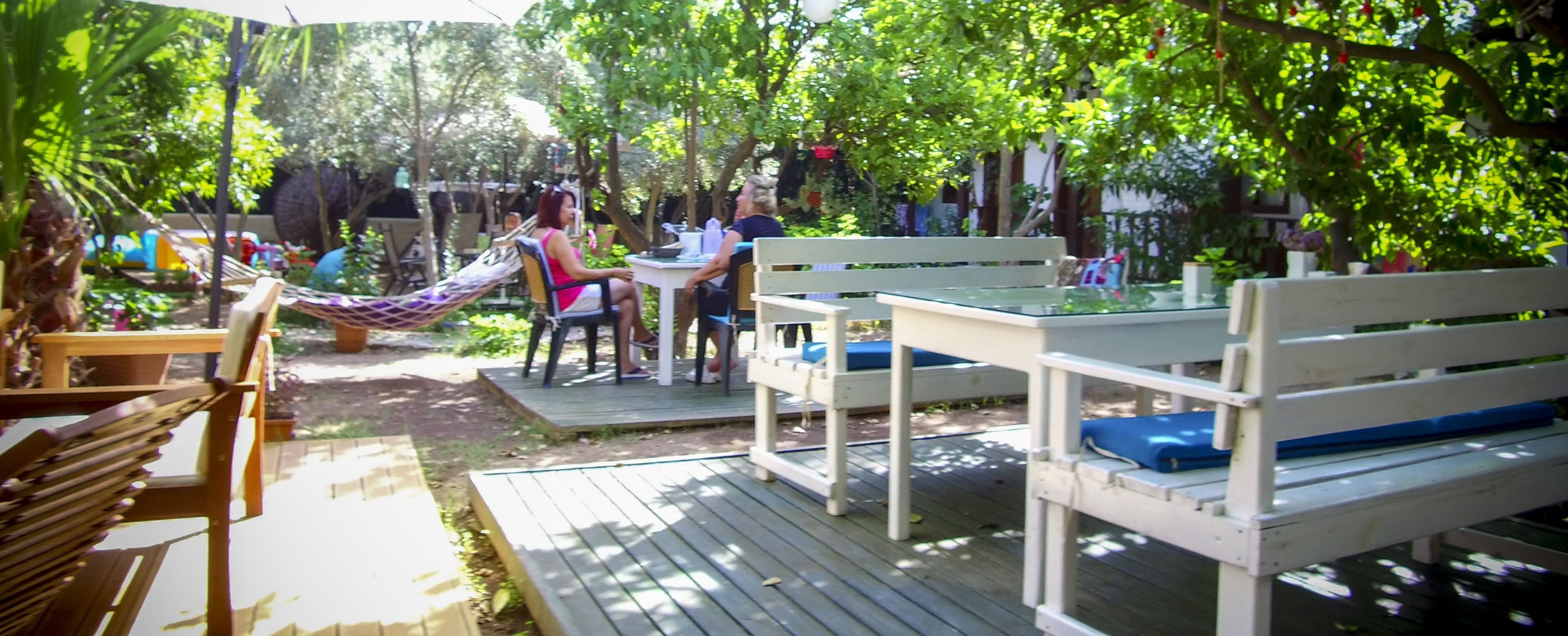 A wooden deck with a hammock, a table, and benches.