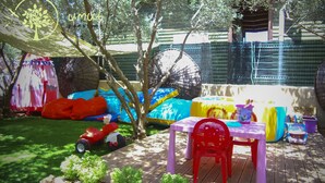A colorful outdoor seating area with a table and chairs, surrounded by trees and a wooden deck. - Umut Otel & Beach (Marmaris)