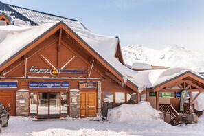 A wooden mountain lodge with a sign reading "Pierre & Cie" and "Les Temples du Soleil." - Résidence Le Schuss (Les Belleville)