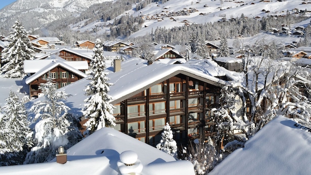 A snow-covered mountain village with wooden cabins and a large lodge with a balcony. - Hotel Kreuz Lenk (Lenk)