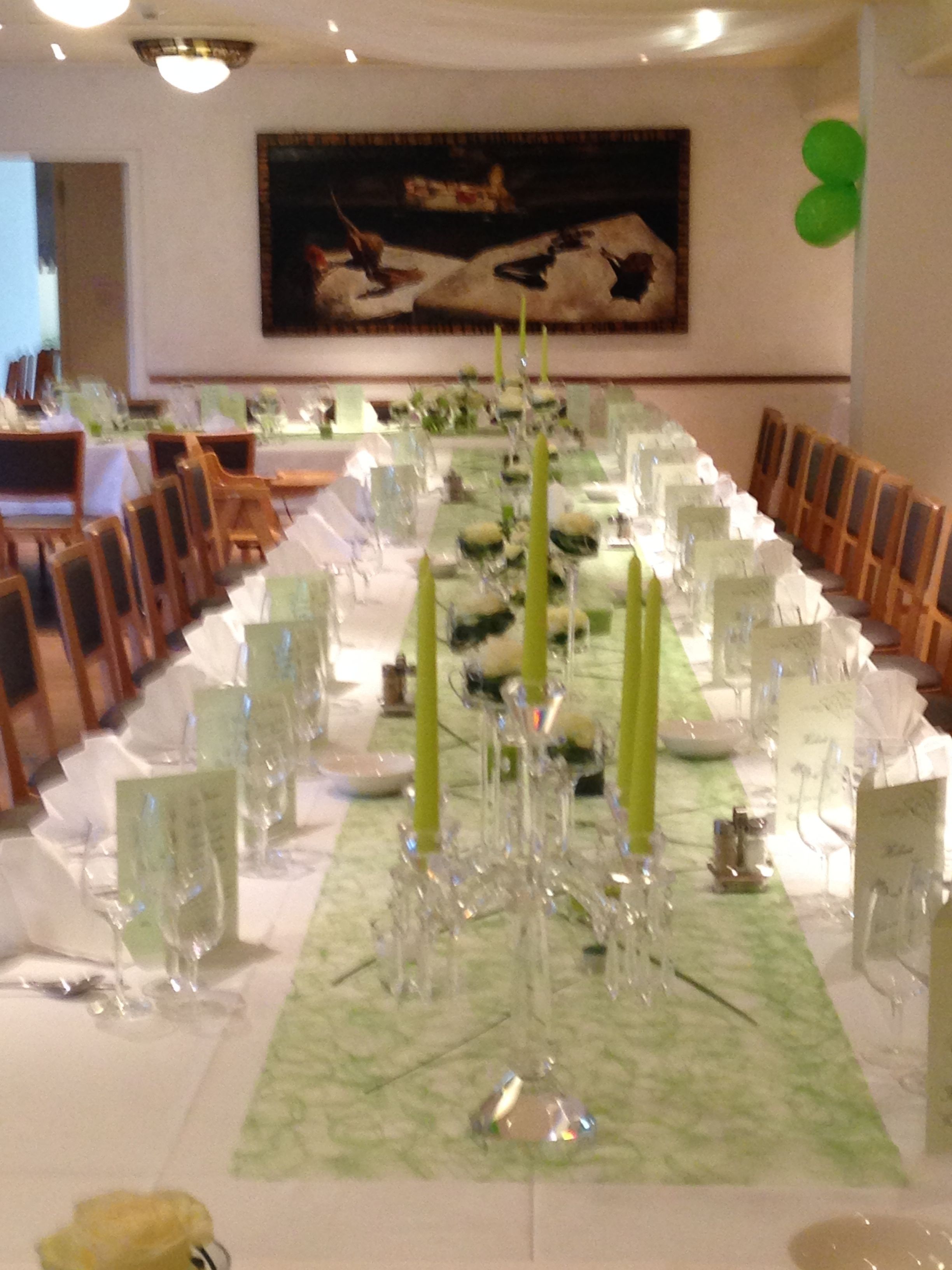 Una larga mesa de comedor preparada para un evento formal, con velas, cristalería y tarjetas de lugar.