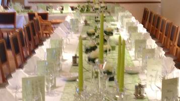 Una larga mesa de comedor preparada para un evento formal, con velas, cristalería y tarjetas de lugar.