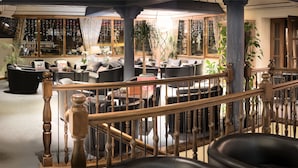 A spacious lobby with multiple seating areas, a staircase with wooden railings, and a bookshelf with various items. - Hotel Kreuz Lenk (Lenk)