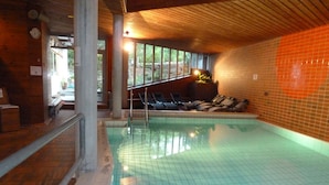 An indoor swimming pool with tiled walls and a wooden ceiling. - Hotel Kreuz Lenk (Lenk)