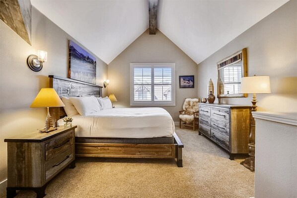Relax in this serene bedroom with a large bed, bedside tables, and a dresser.