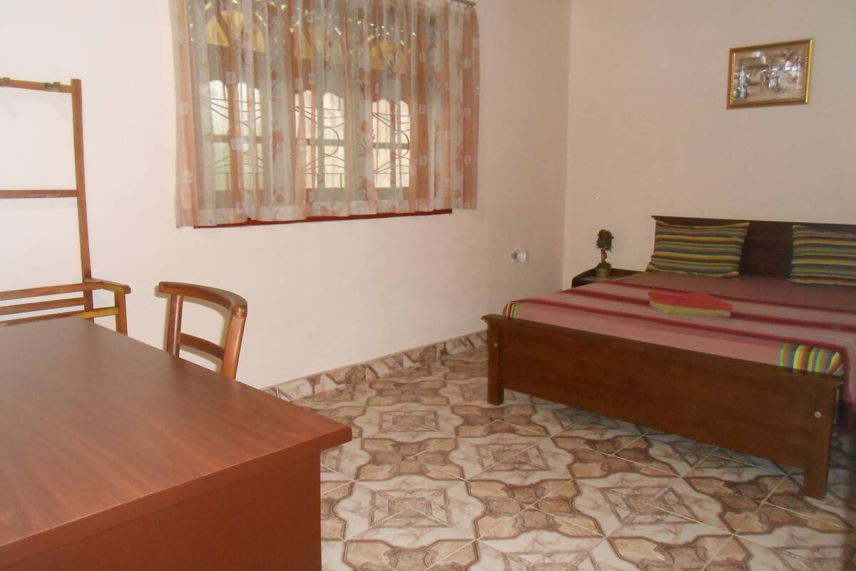 Un dormitorio con una cama de madera, una mesita y sillas.
