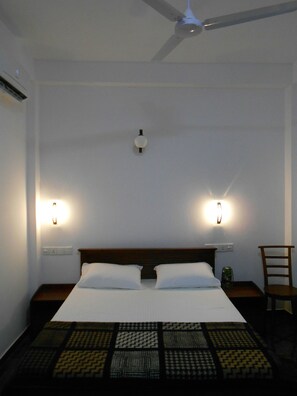 A hotel room with a bed, two bedside lamps, a ceiling fan, and a chair. - Villa Rodrigo (Negombo)