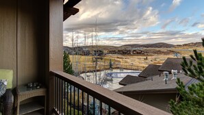 Ein Balkon mit Blick auf ein Wohngebiet, einschließlich Häusern und einer hügeligen Landschaft.