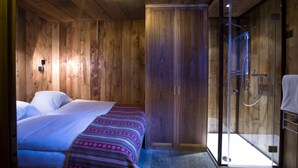 Een kamer met houten vloeren, een bed, een kledingkast en een douchecabine met glazen wanden.