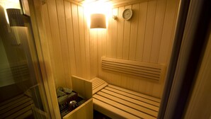 Een sauna met houten banken, een wandheater en een klok.