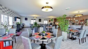 A modern restaurant with checkered walls, multiple dining areas, and a bar. - Logis L'auberge de Moricq (Angles)