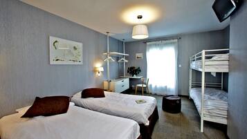 Une chambre d’hôtel avec deux lits, un bureau, une chaise, une télévision et un lit superposé.