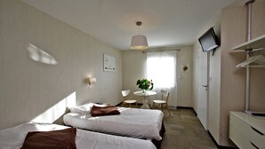 A hotel room with two beds, a desk, a chair, a television, and a wardrobe. - Logis L'auberge de Moricq (Angles)