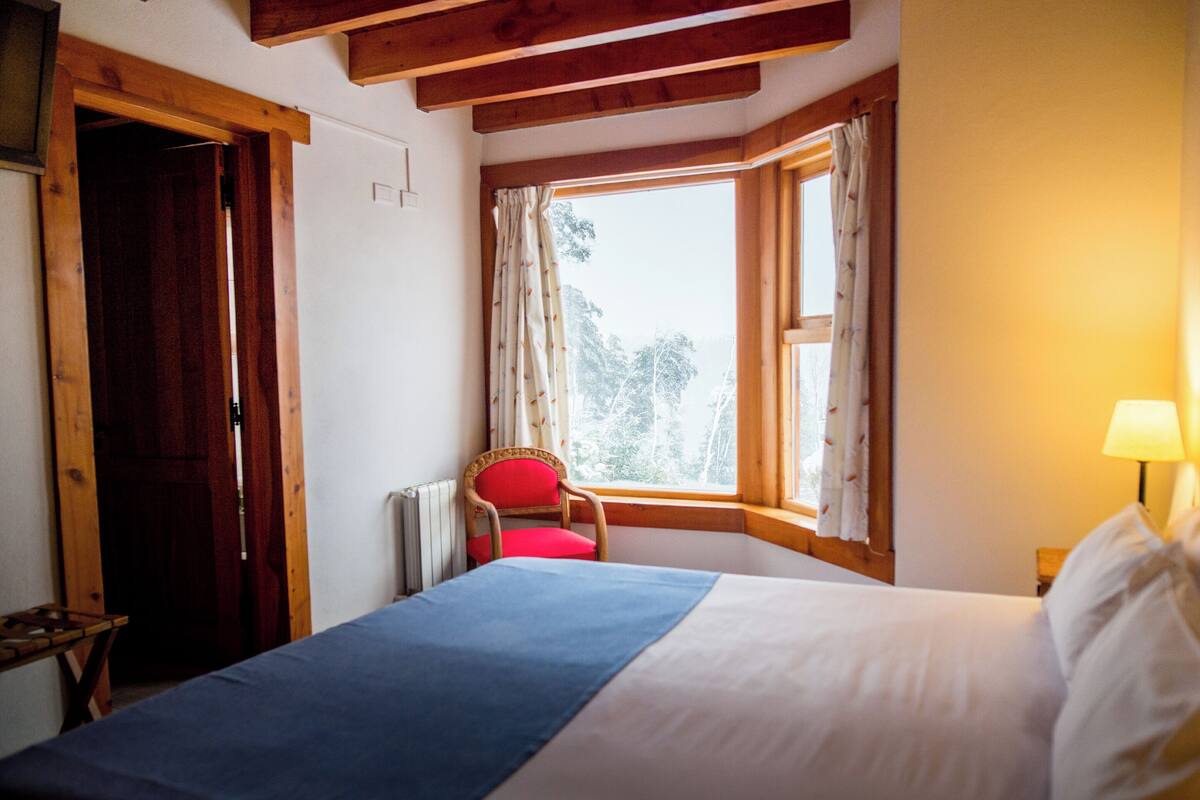Une chambre à coucher avec un lit, une chaise, une fenêtre et une lampe.