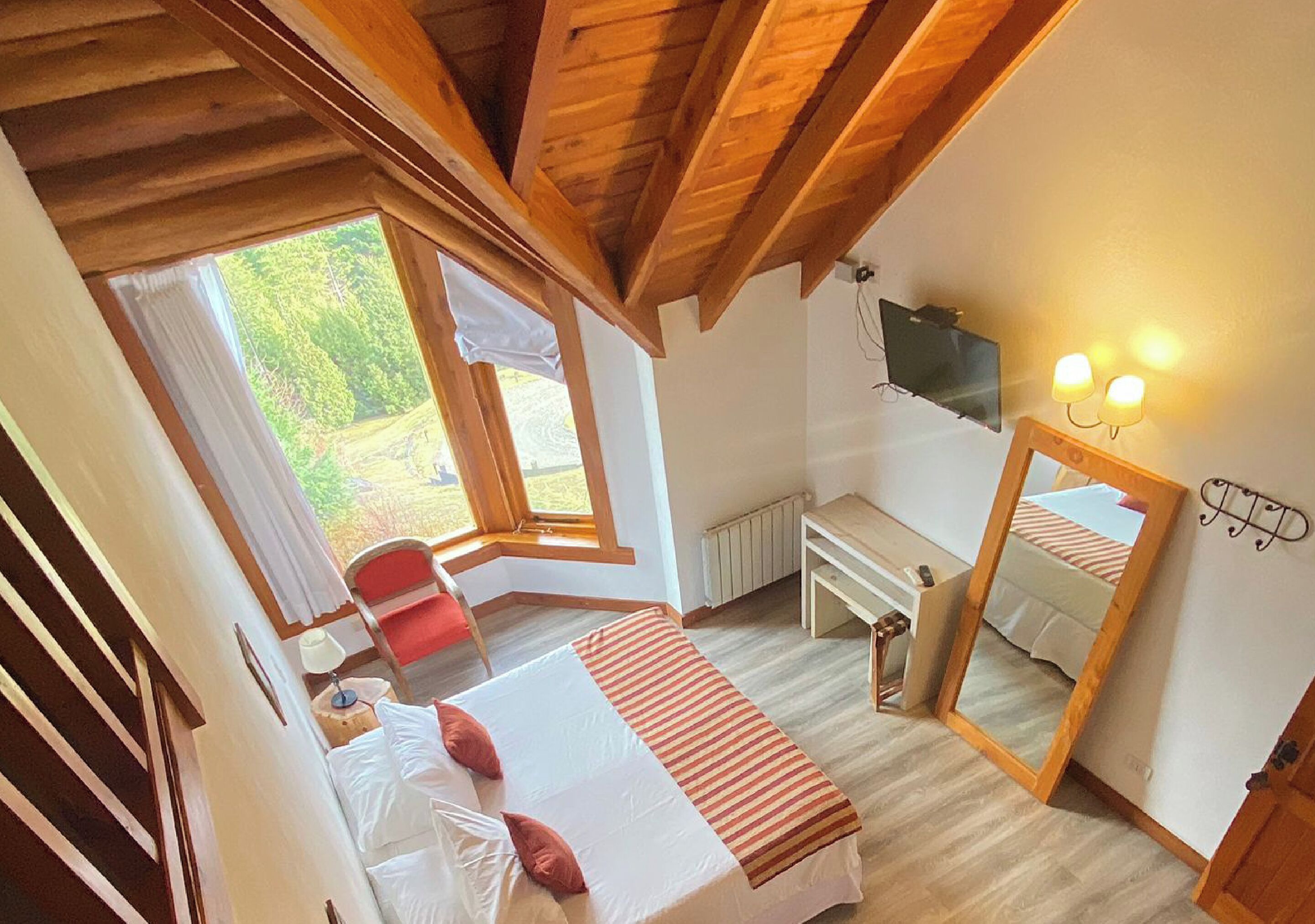 Un dormitorio con cama, escritorio, silla, televisor y ventana.