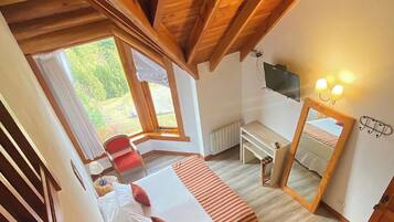 Un dormitorio con cama, escritorio, silla, televisor y ventana.