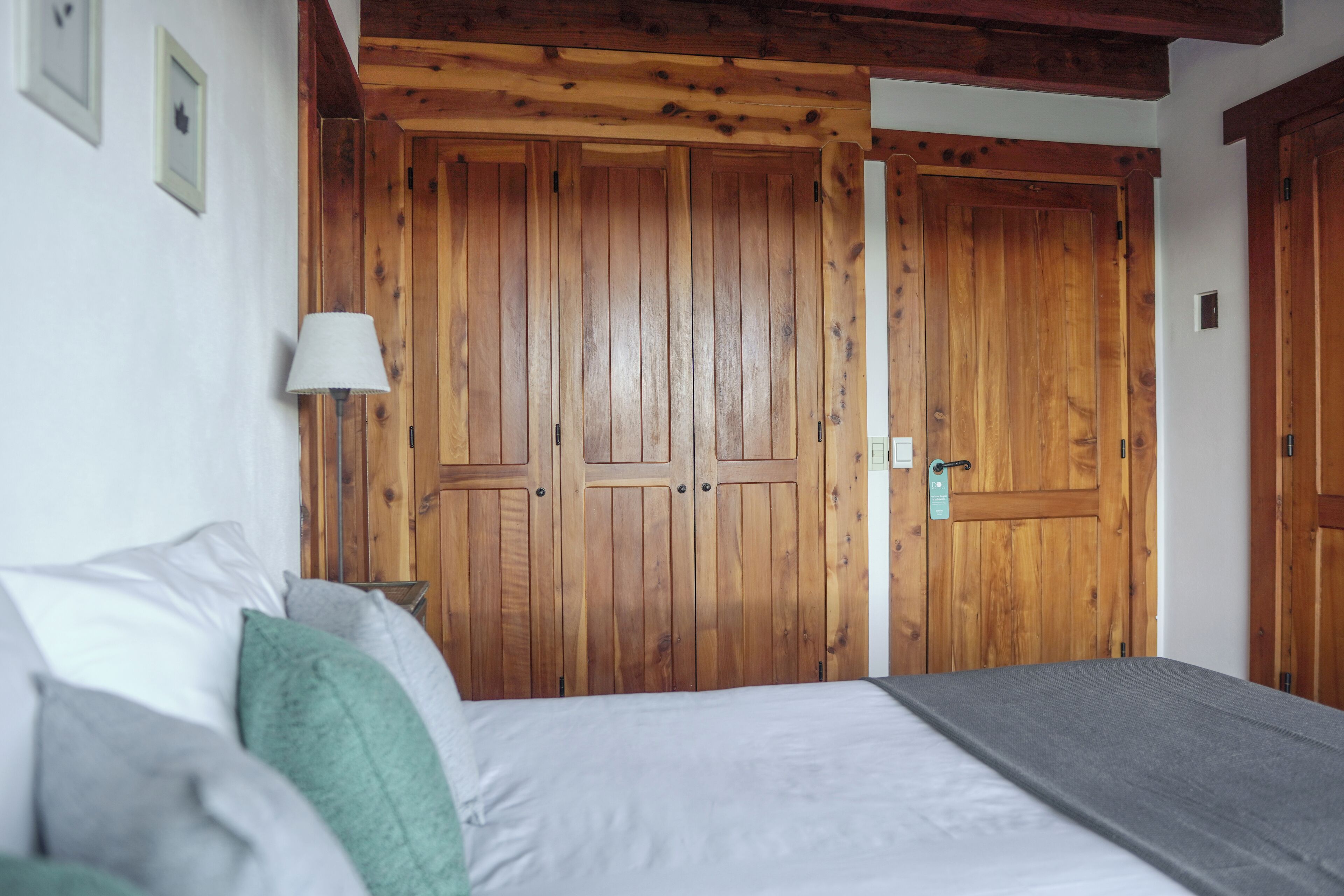 A bedroom with a bed, pillows, a lamp, and wooden wardrobes.
