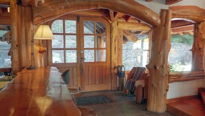 A wooden interior with a bar area, stone walls, and a large window. - El Bosque by DOT Tradition (Villa La Angostura)