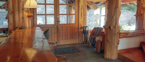 Un interior de madera con una zona de bar, paredes de piedra y un ventanal grande.