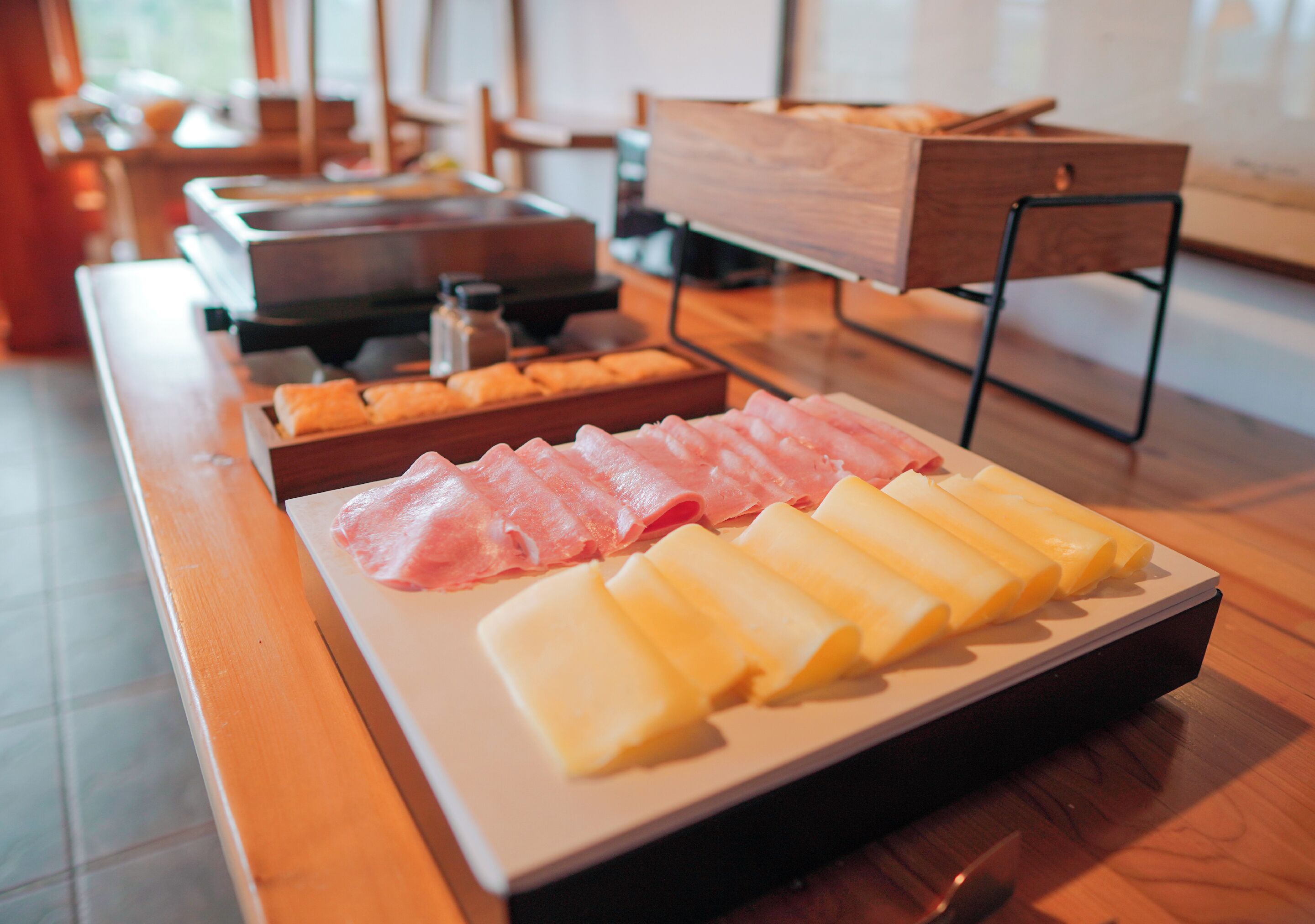 A wooden table with a variety of cheeses and cured meats.