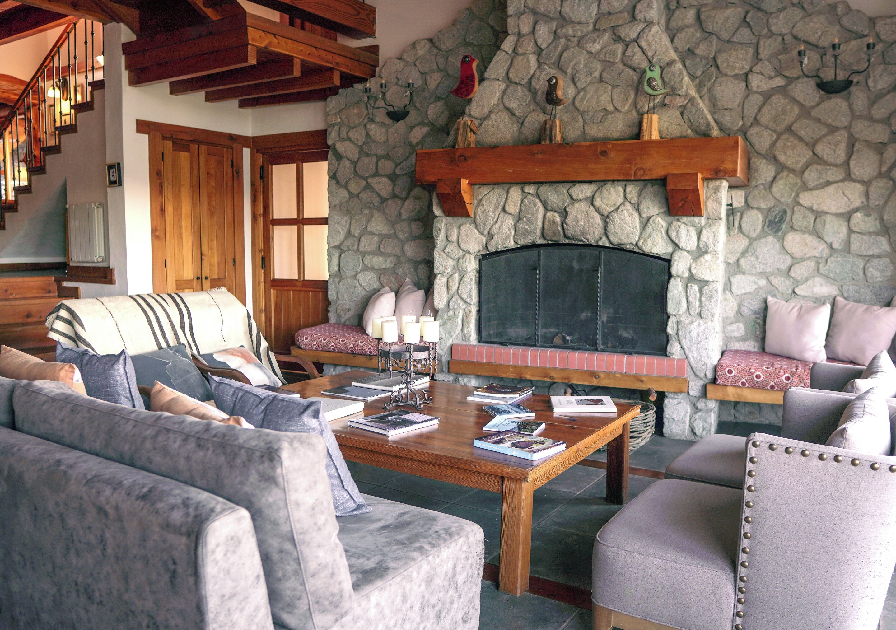 Un salón acogedor con chimenea de piedra, vigas de madera y asientos cómodos.